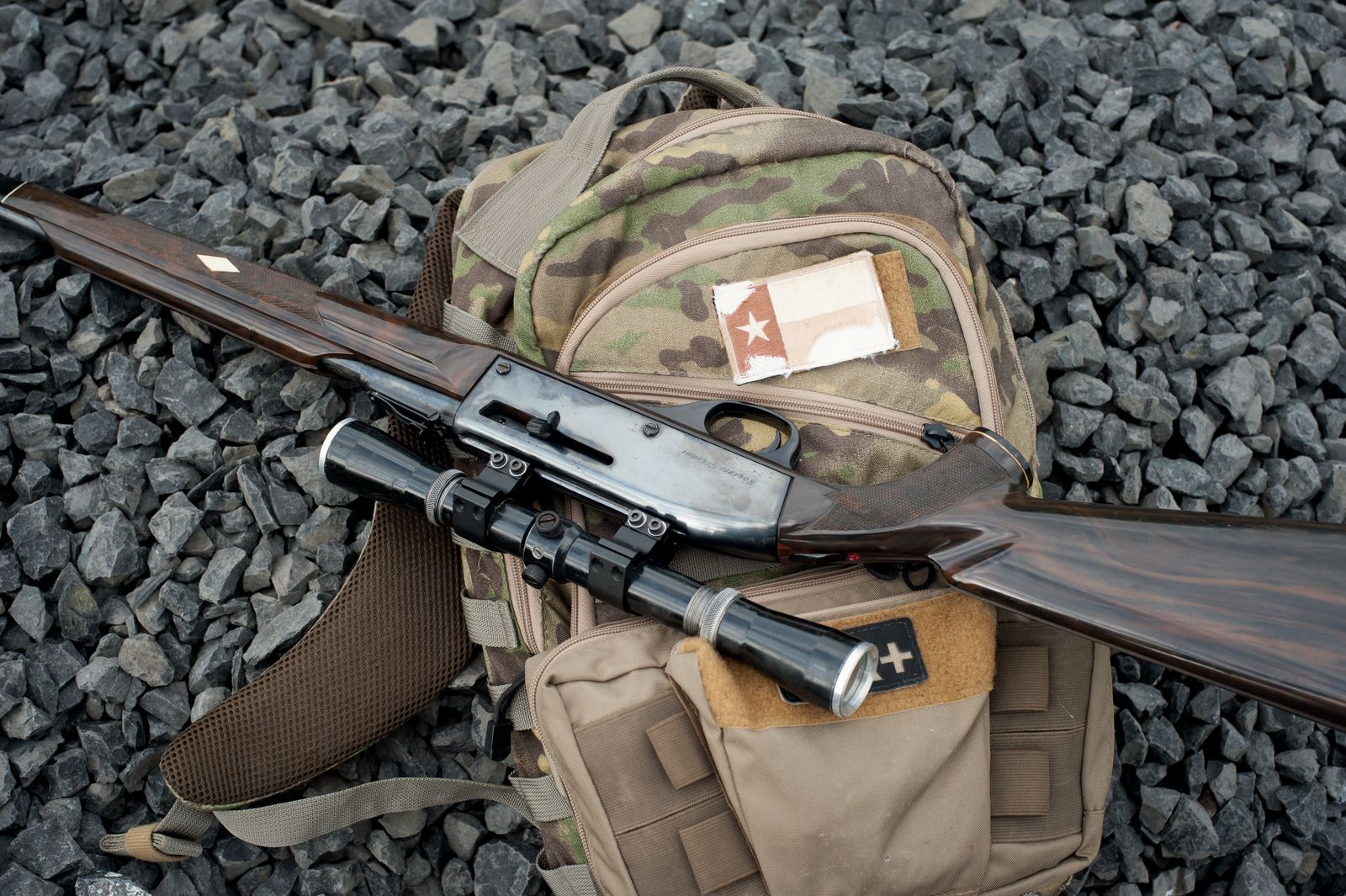 Scoped hunting rifle on a camouflage backpack
